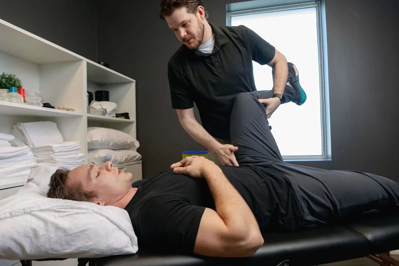 Cole supporting a client’s leg during hands-on chiropractic treatment at iON